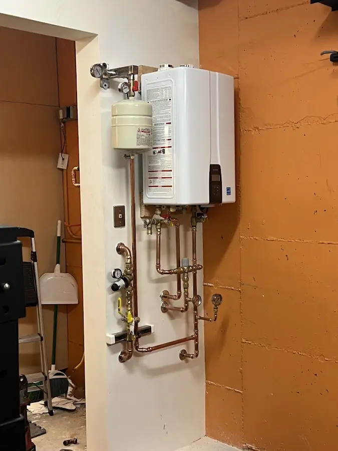 Plumbing technician inspecting water heater connections in Maple Grove